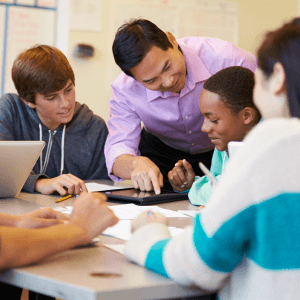 Teacher speaking with a diverse group of teenage students at desk