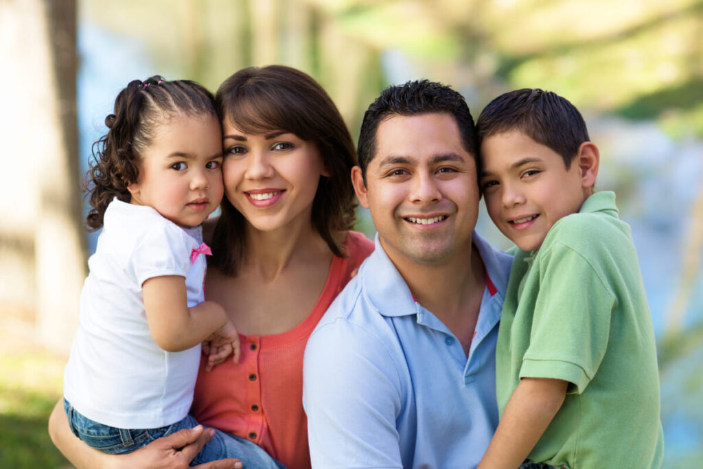 Young latin family of mother father daughter and son smiling for photo