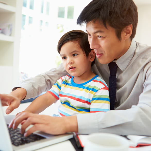 Busy Asian father working from home with Autistic son on lap