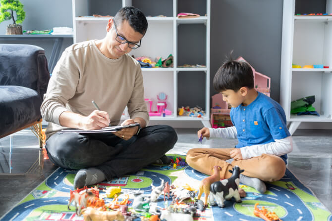 Professional ABA observing little boy playing with toys at the psychotherapy session